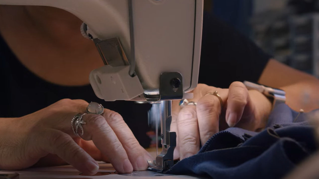 Hands using sewing machine on blue uniform