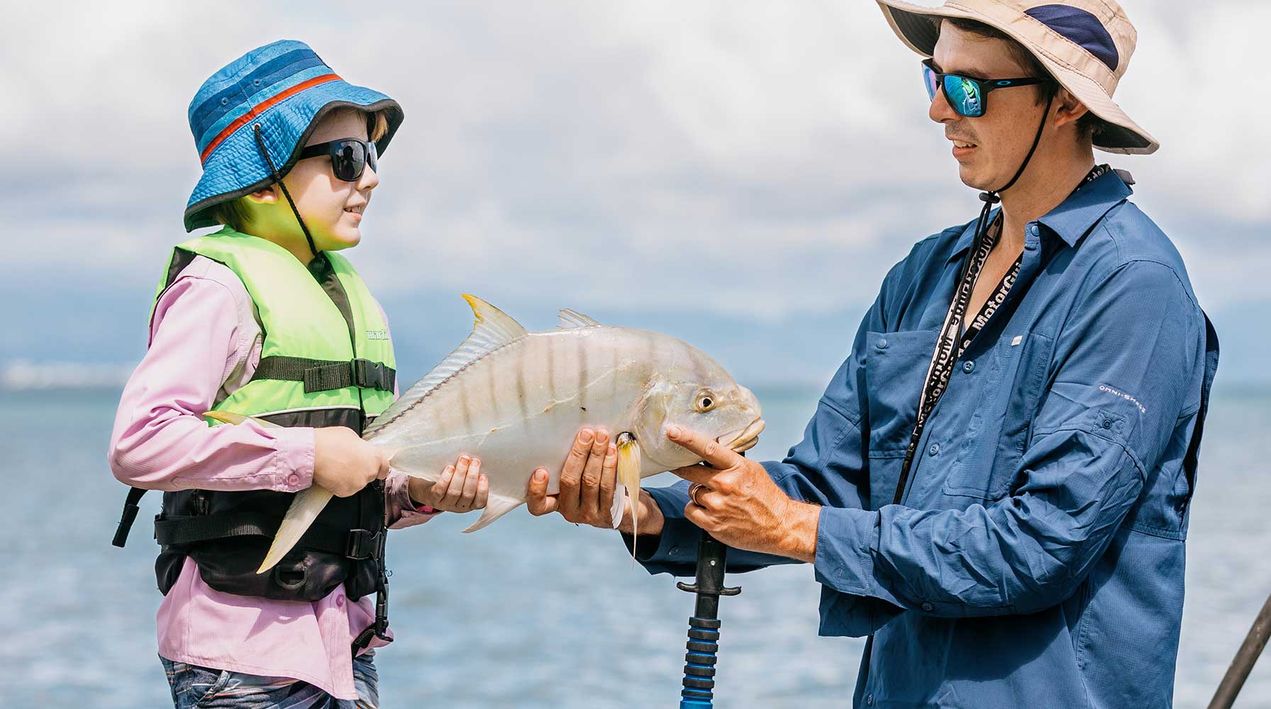 Father and son holding fish on boat