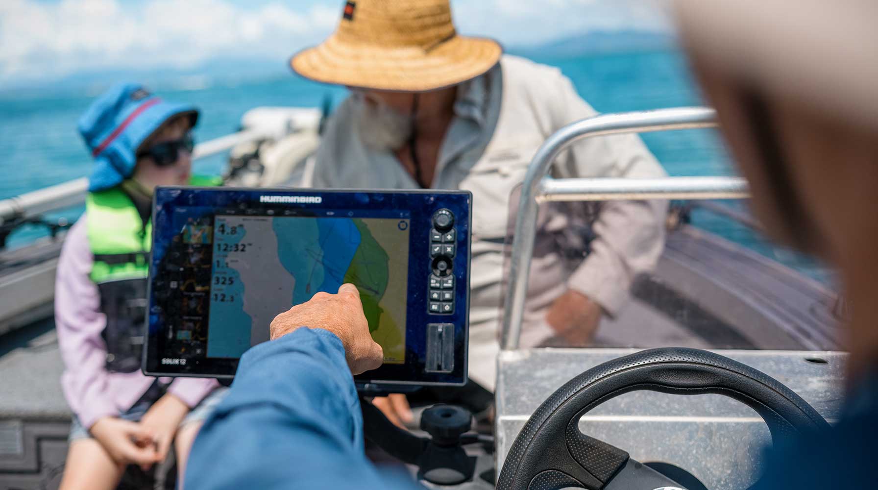 Skipper on boat pointing toward chartplotter