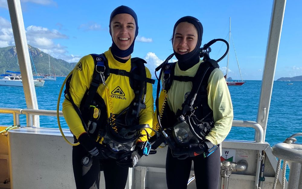 Two commercial divers stand on a boat.