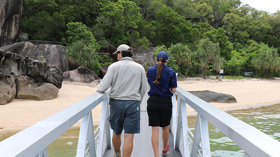 Two staff walking along pier towards beach