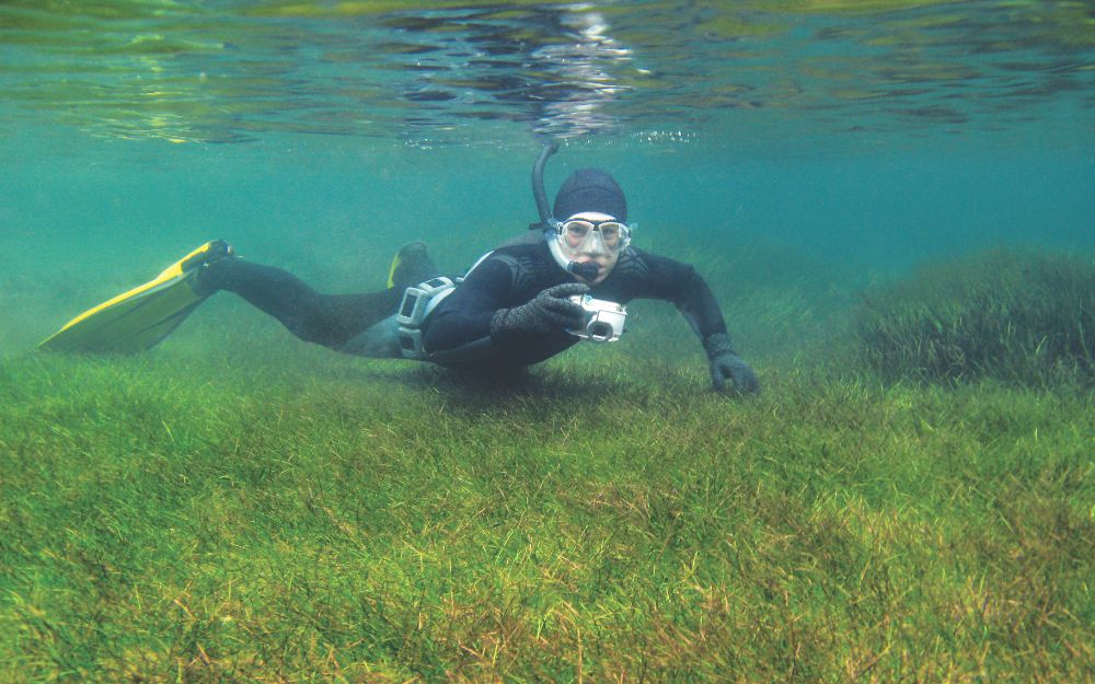 Man snorkelling underwater with camera.