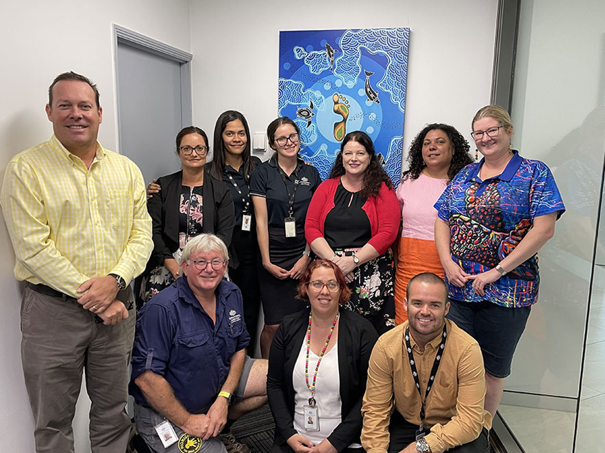 Members of the RAP working group standing in front of Traditional Owner artwork