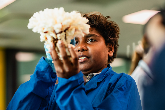 Student in a classroom examining a coral specimen