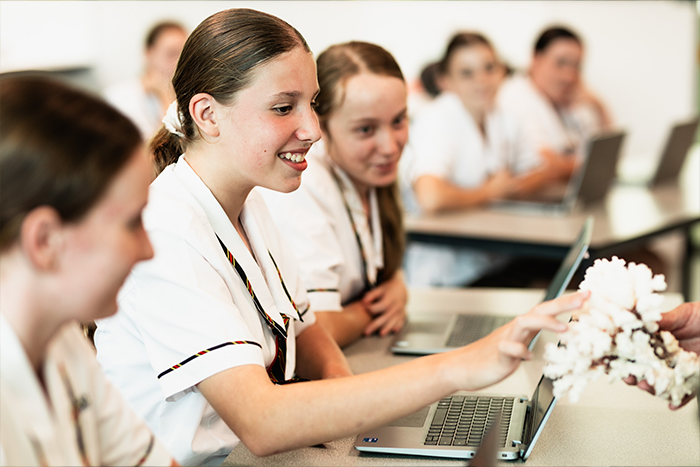 Students in a classroom examining a coral specimen, guided by Matthew Radburnd