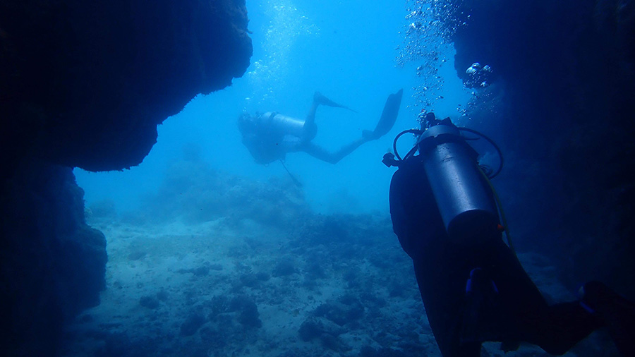 Two scuba divers traversing through underwater structure