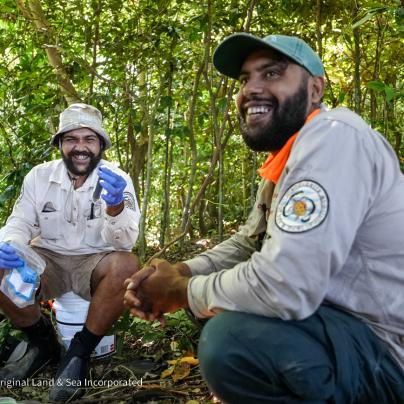 Two men holding samples in the forest