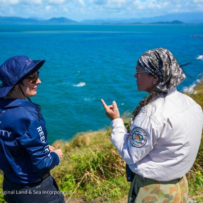 Two women standing talking together on a cliff overlooking the ocean