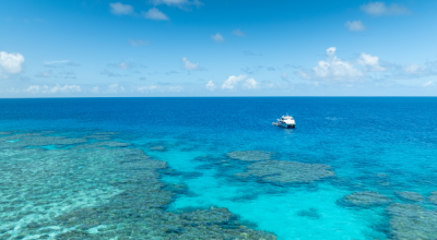 A white boat floats over coral gardens in turquoise water. (C): Commonwealth of Australia: Reef Authority