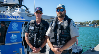 Two compliance officers stand in front of a compliance vessel