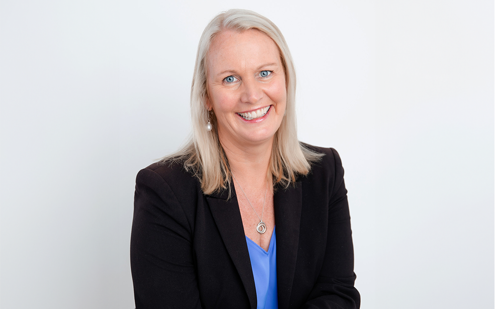 A smiling woman with shoulder-length hair, wearing blazer