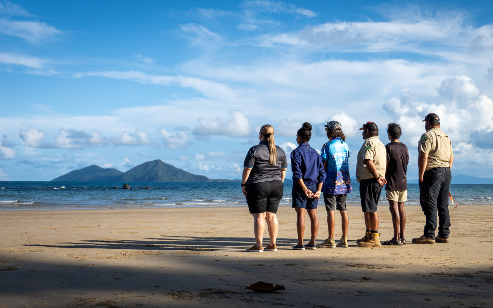Six people standing on the beach looking out into the horizon. (C): Commonwealth of Australia: Reef Authority