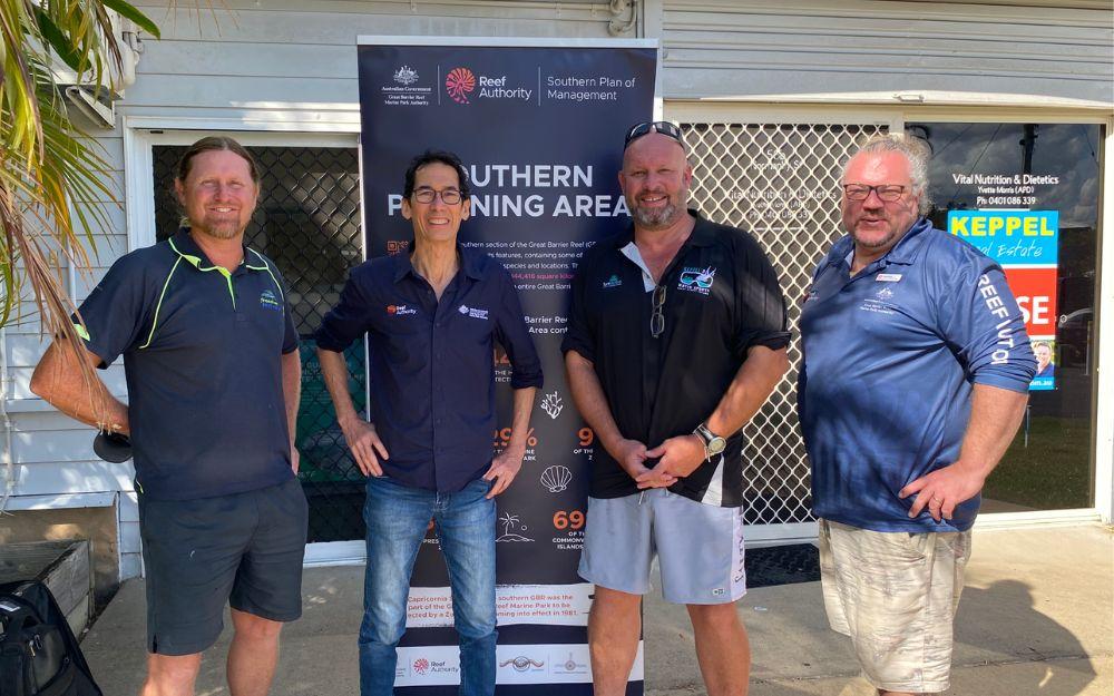 Four men stand in front of a pull up banner.
