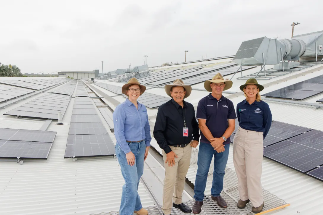 Group standing on airport rooftop with solar panels in background